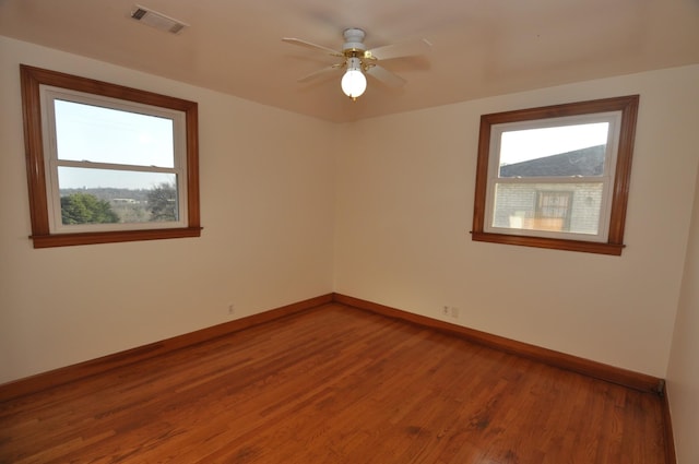 spare room with wood-type flooring, a healthy amount of sunlight, and ceiling fan