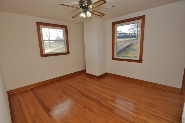 unfurnished room featuring wood-type flooring, plenty of natural light, and ceiling fan