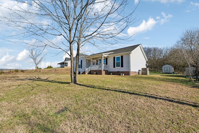 view of front of house featuring central AC, covered porch, a shed, and a front yard