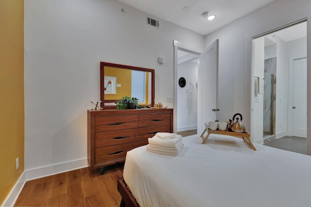 bedroom with connected bathroom and hardwood / wood-style floors