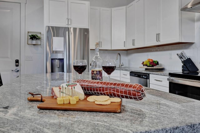 kitchen featuring white cabinetry, light stone countertops, extractor fan, and appliances with stainless steel finishes