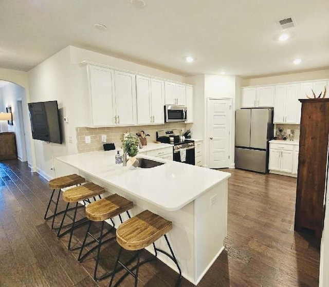 kitchen featuring kitchen peninsula, white cabinetry, a breakfast bar, and appliances with stainless steel finishes