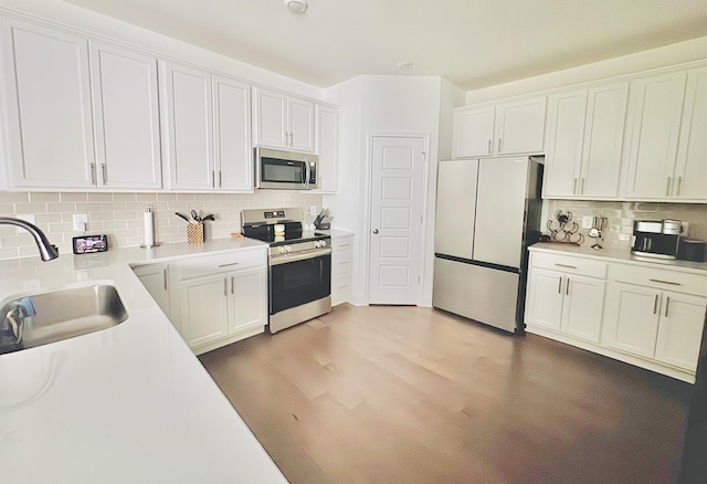 kitchen featuring sink, stainless steel appliances, light hardwood / wood-style flooring, decorative backsplash, and white cabinets