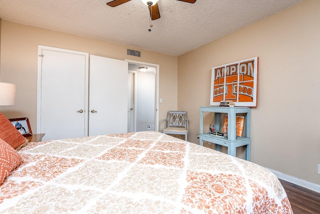 bedroom with ceiling fan, a textured ceiling, a closet, and dark hardwood / wood-style flooring