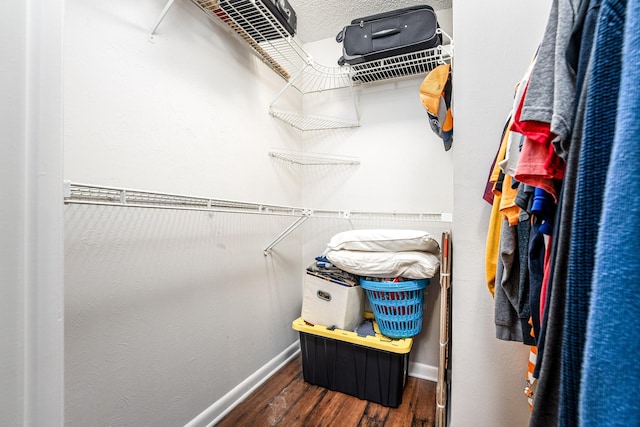 walk in closet with dark hardwood / wood-style floors