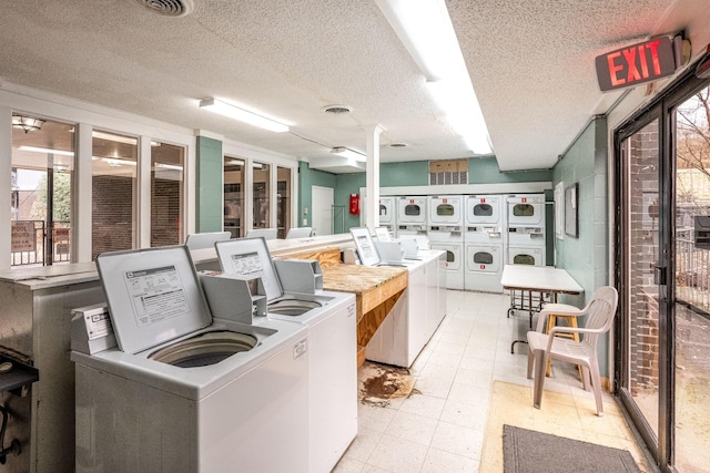 clothes washing area with a textured ceiling and independent washer and dryer