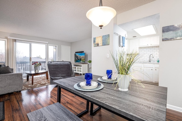 dining space featuring a textured ceiling, dark hardwood / wood-style flooring, and sink