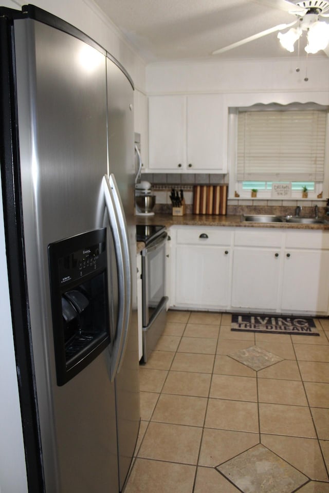 kitchen with appliances with stainless steel finishes, ceiling fan, sink, light tile patterned floors, and white cabinetry