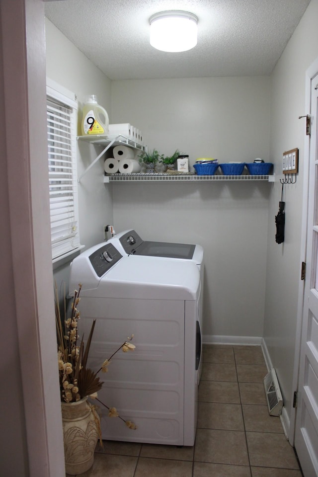 washroom with washing machine and dryer, dark tile patterned floors, and a textured ceiling