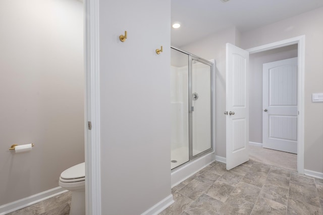 bathroom featuring a shower with door and toilet