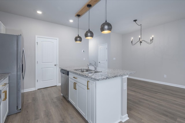 kitchen featuring sink, white cabinetry, appliances with stainless steel finishes, pendant lighting, and light stone countertops