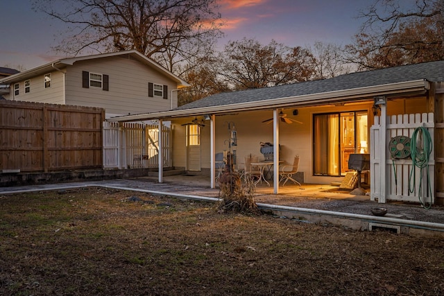 back house at dusk with a patio area and ceiling fan