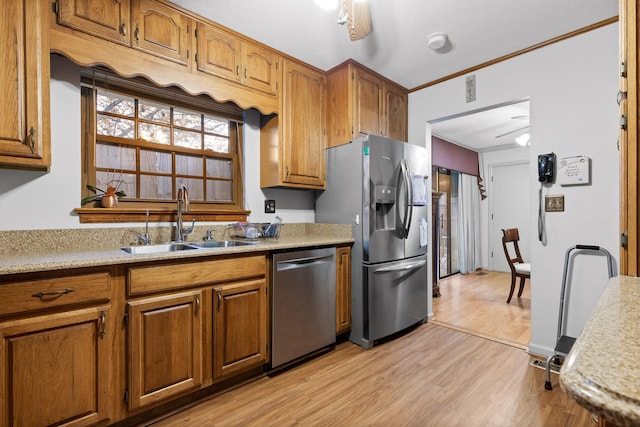 kitchen featuring sink, ceiling fan, light wood-type flooring, ornamental molding, and appliances with stainless steel finishes