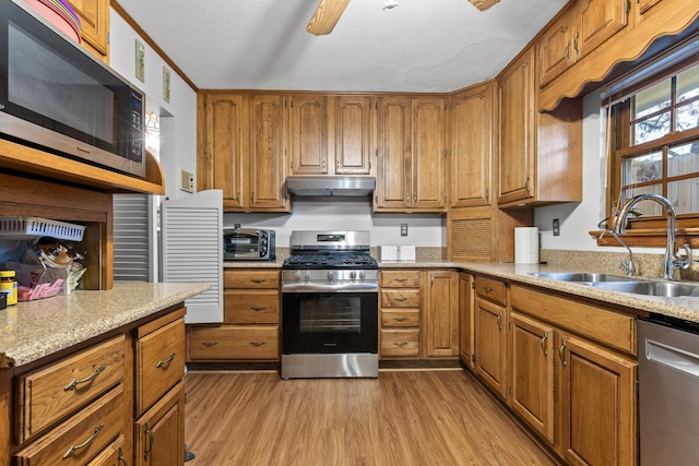 kitchen featuring light wood-type flooring, a textured ceiling, stainless steel appliances, ceiling fan, and sink