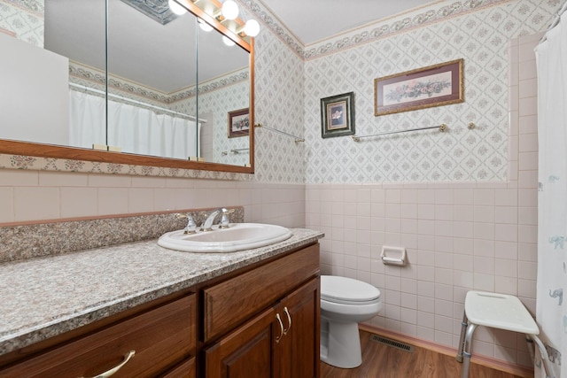 bathroom with hardwood / wood-style floors, vanity, toilet, and tile walls