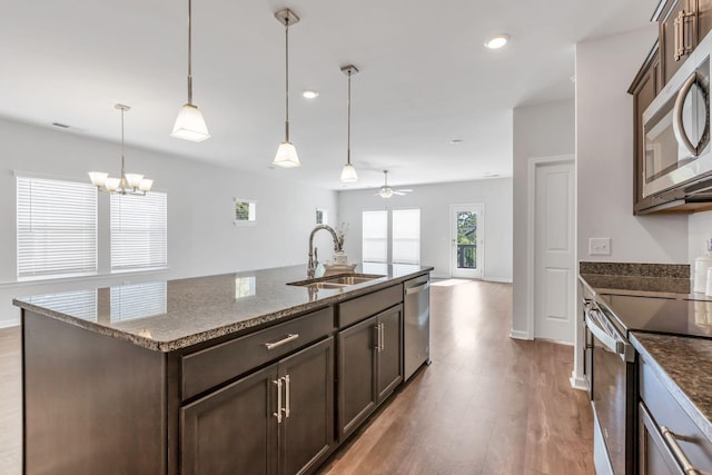 kitchen featuring a kitchen island with sink, ceiling fan with notable chandelier, sink, light hardwood / wood-style flooring, and stainless steel appliances