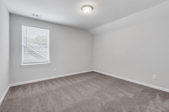 carpeted spare room with vaulted ceiling