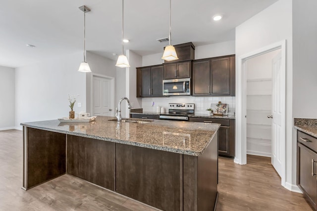 kitchen featuring pendant lighting, dark brown cabinets, stainless steel appliances, and hardwood / wood-style flooring