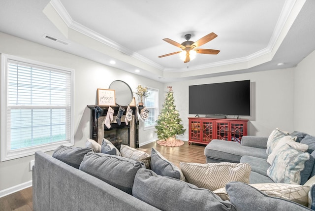 living room featuring dark hardwood / wood-style flooring, a tray ceiling, and crown molding