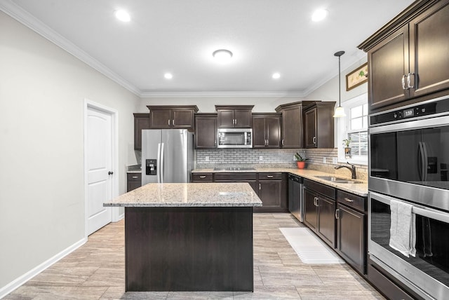 kitchen with appliances with stainless steel finishes, crown molding, sink, pendant lighting, and a center island