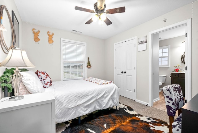 carpeted bedroom with connected bathroom, ceiling fan, and a closet