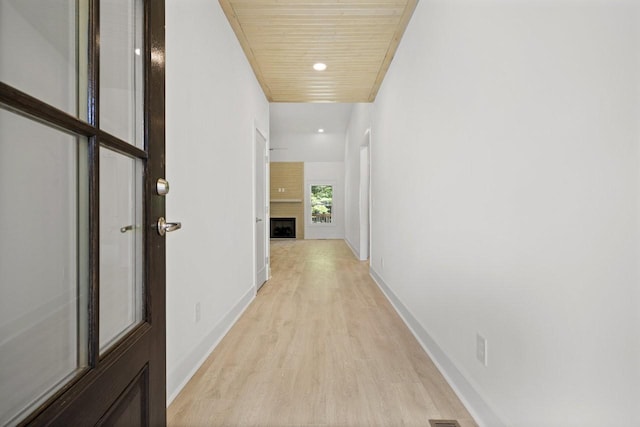 corridor featuring light hardwood / wood-style flooring and wooden ceiling