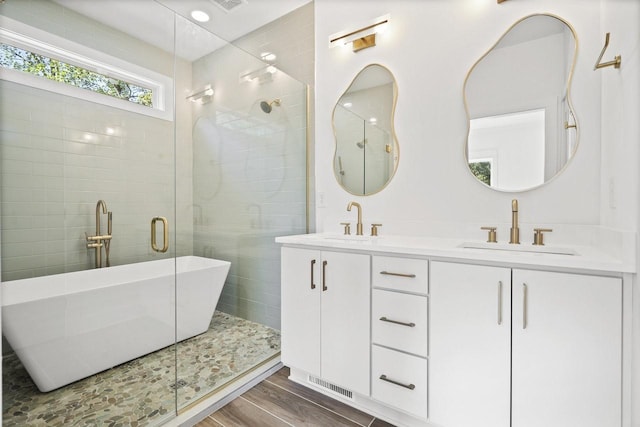 bathroom with hardwood / wood-style floors, vanity, and shower with separate bathtub