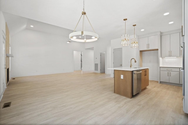 kitchen with sink, hanging light fixtures, stainless steel dishwasher, a kitchen island with sink, and light wood-type flooring