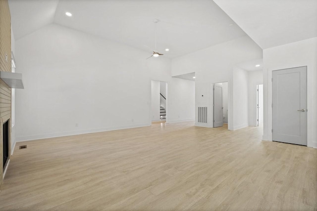 unfurnished living room with high vaulted ceiling, light hardwood / wood-style floors, a brick fireplace, and ceiling fan