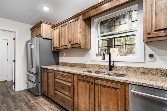 kitchen featuring stainless steel appliances, light stone counters, dark wood-type flooring, and sink