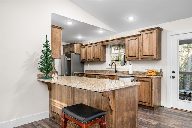 kitchen with a breakfast bar, vaulted ceiling, dark hardwood / wood-style floors, kitchen peninsula, and stainless steel appliances