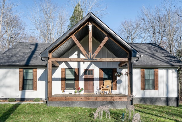 rear view of house featuring a lawn and covered porch