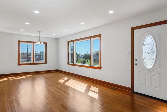 foyer featuring a healthy amount of sunlight, a notable chandelier, and wood-type flooring