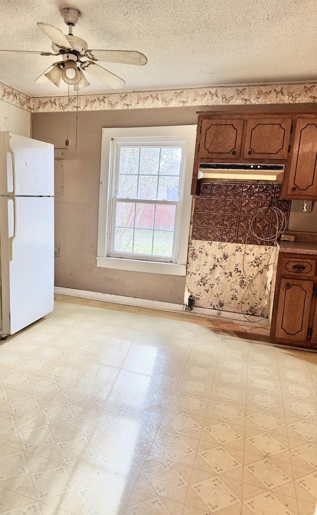 kitchen featuring ceiling fan, white fridge, and a textured ceiling