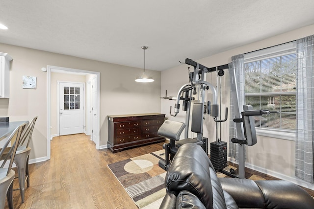 workout area featuring a textured ceiling and light wood-type flooring