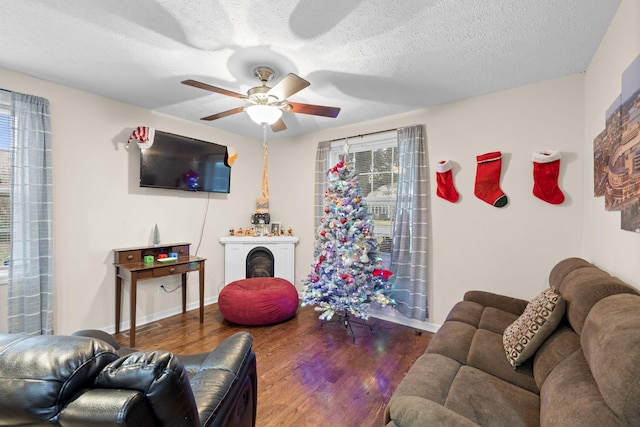 living room with a textured ceiling, dark hardwood / wood-style floors, and ceiling fan