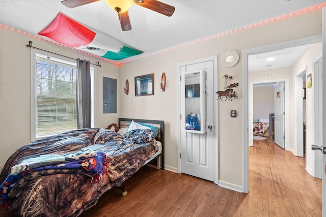 bedroom featuring a textured ceiling, light wood-type flooring, electric panel, and ceiling fan