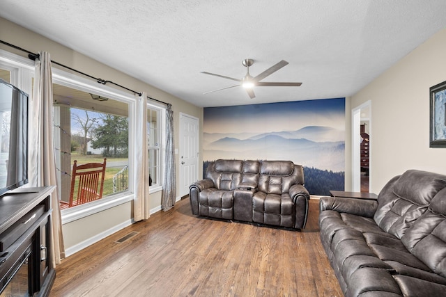 living room featuring ceiling fan, hardwood / wood-style floors, and a textured ceiling