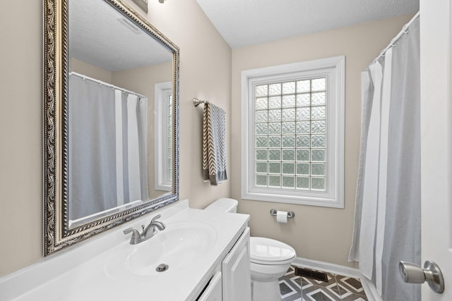 bathroom with tile patterned flooring, a textured ceiling, vanity, and toilet