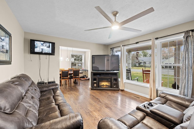 living room featuring a fireplace, a textured ceiling, hardwood / wood-style flooring, and ceiling fan