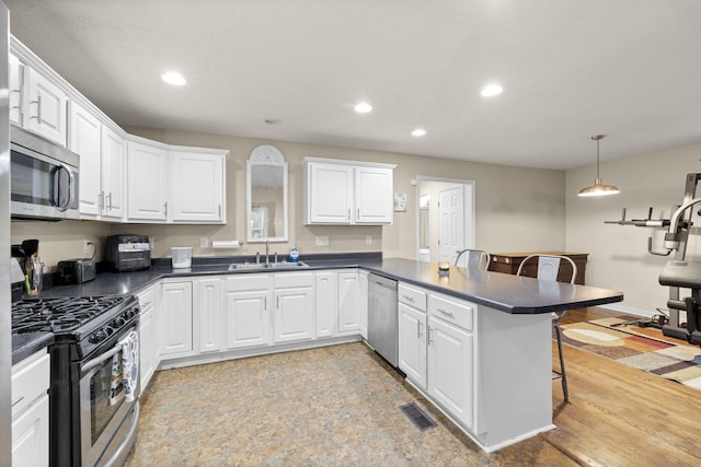 kitchen with kitchen peninsula, a kitchen breakfast bar, stainless steel appliances, pendant lighting, and white cabinets