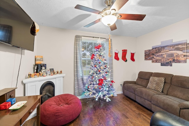 living room with ceiling fan, dark hardwood / wood-style flooring, and a textured ceiling