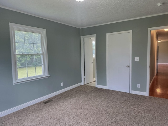 unfurnished bedroom featuring carpet, ornamental molding, and a textured ceiling