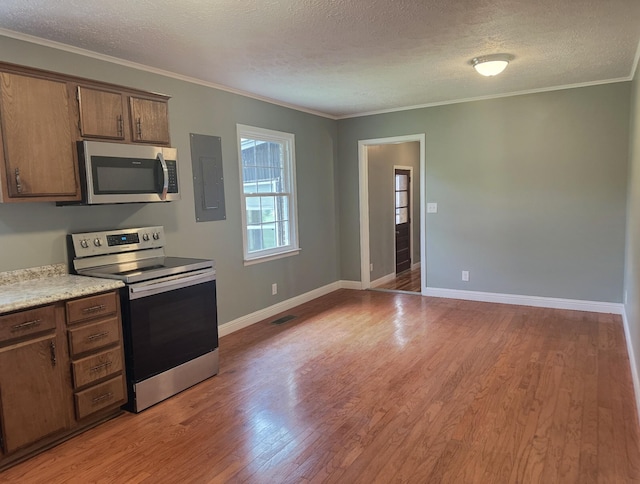 kitchen with electric panel, light wood-type flooring, a textured ceiling, and appliances with stainless steel finishes