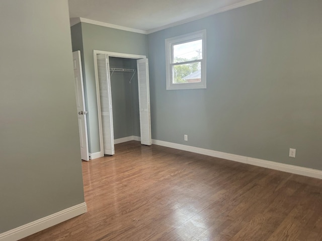 unfurnished bedroom with a closet, ornamental molding, and hardwood / wood-style flooring