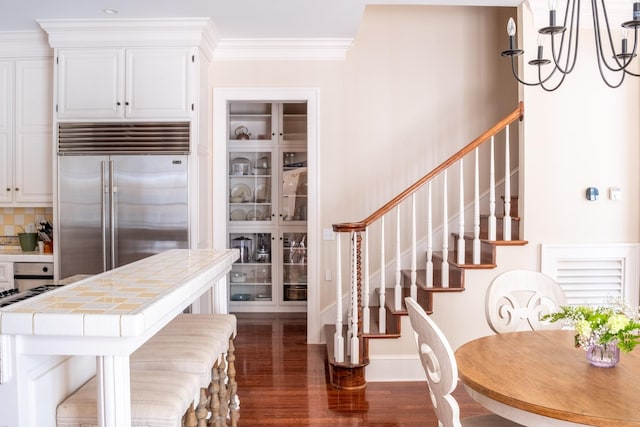 interior space with white cabinets, tile countertops, stainless steel built in fridge, and dark wood-type flooring