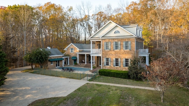 greek revival inspired property featuring a balcony and a front lawn