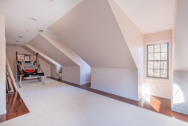 additional living space with hardwood / wood-style floors and vaulted ceiling