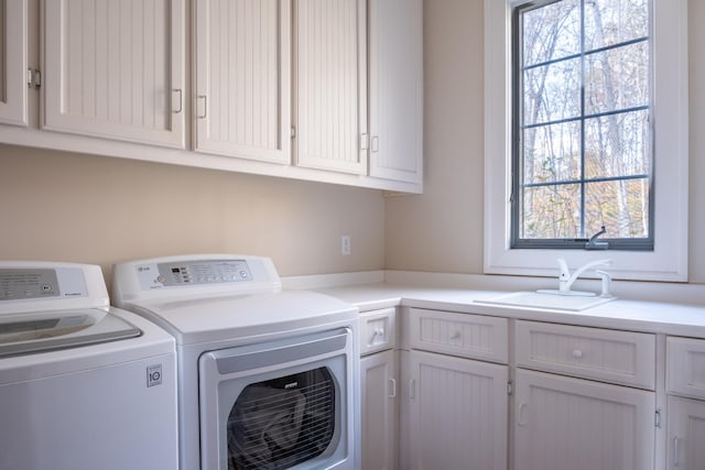 laundry area featuring cabinets, independent washer and dryer, and sink