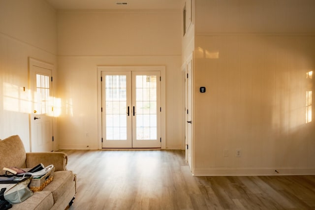 doorway featuring french doors, a high ceiling, ornamental molding, and wood-type flooring